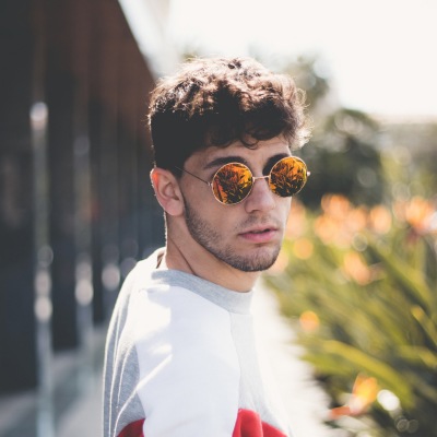 Icon of a young man with sunglasses in a white t-shirt with a garden in the background