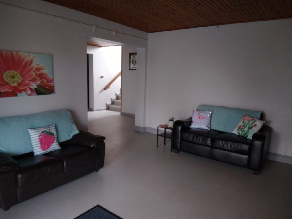 Reception area with two black couches, both with a green throw and colourful cushions