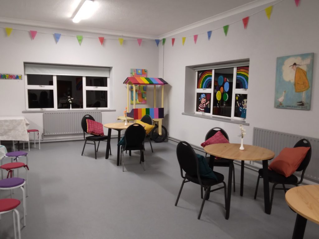 Function room image with adult tables set up and a colourful candy cart in the background