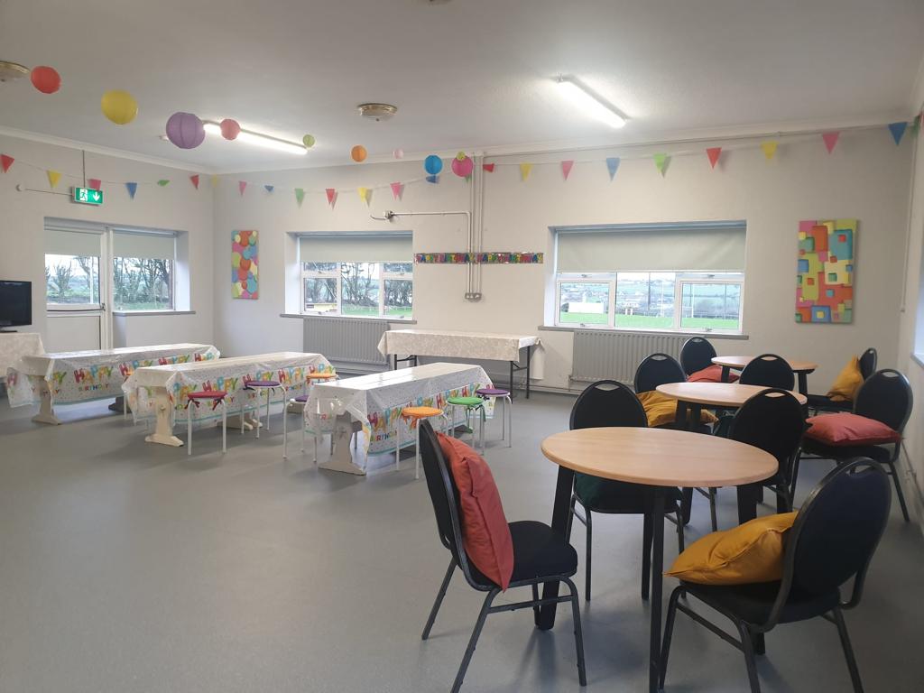 Party room set up with tables and chairs in the room and colourful bunting on the walls.