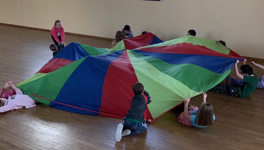 Children hold a multi coloured parachute