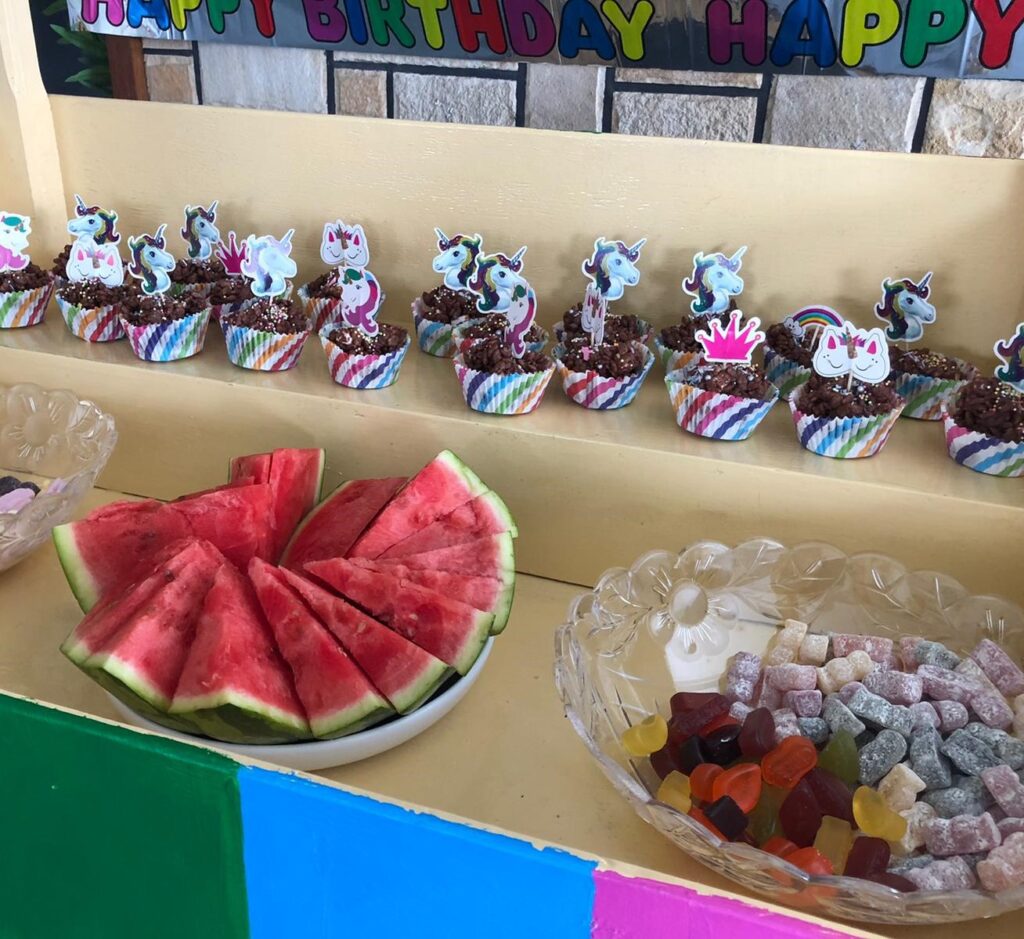 Party treats layout with watermelon, buns and sweets in a bowl